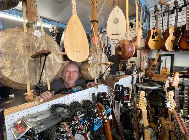 Mitch Kopp, owner of Full Circle Music, Inc., in the shop surrounded by instruments